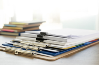 stack of clipboards and books on white background