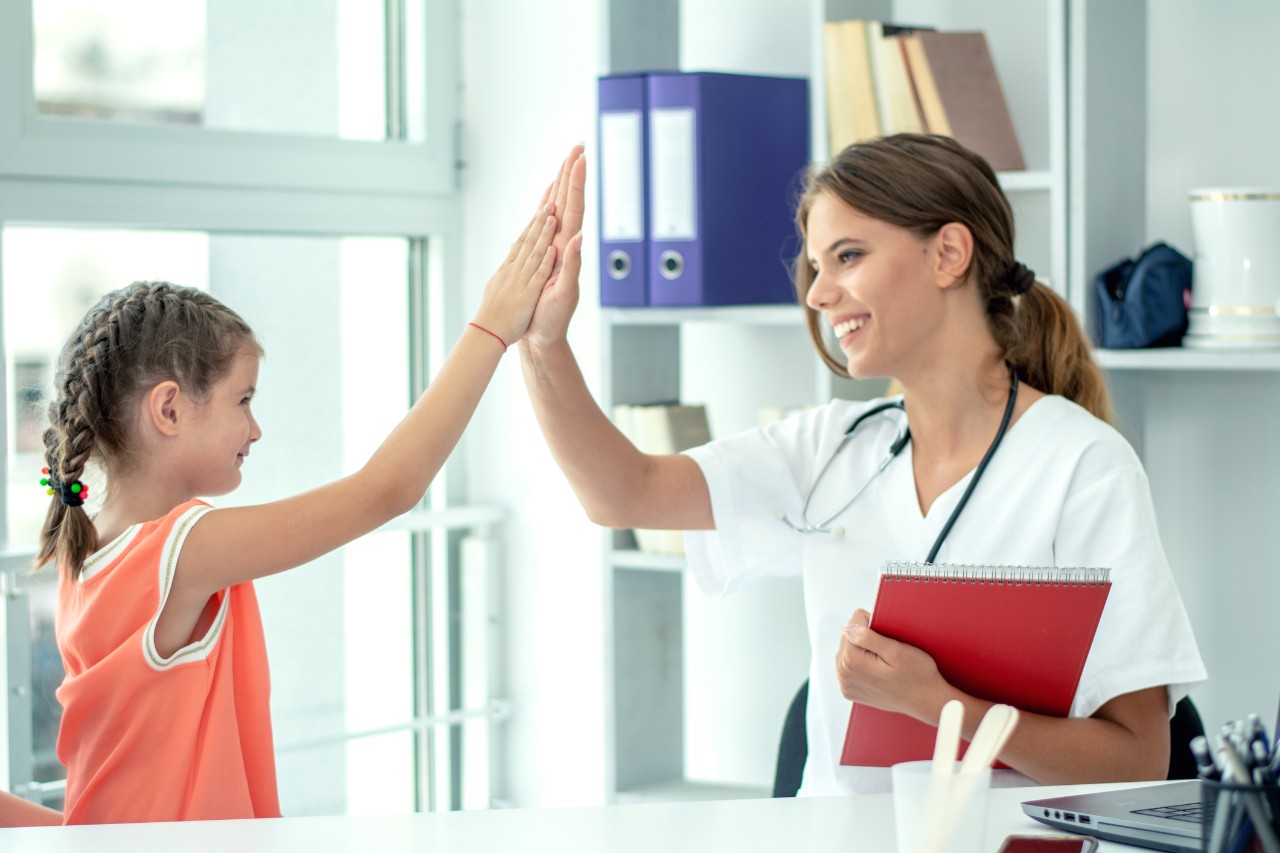 1176812070 Cute girl and paediatrician doing high five
