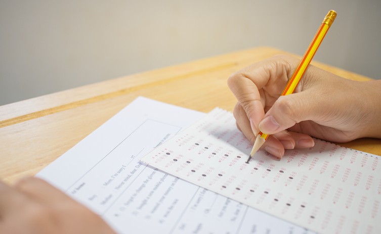 881192080 Students hands taking exams, writing examination room with holding pencil on optical form of standardized test with answers and english paper sheet on row desk chair doing final exam in classroom.