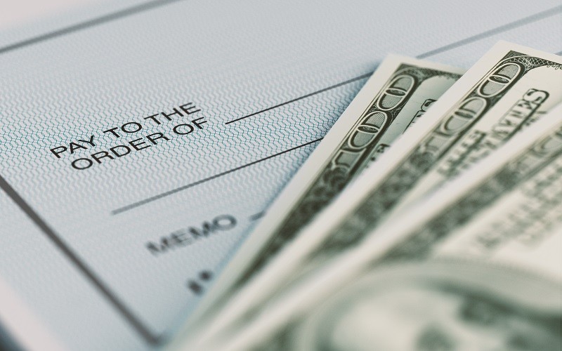 610233664 Close-up picture of a personal check and American Dollars with selective focus. Great use for financial concepts.