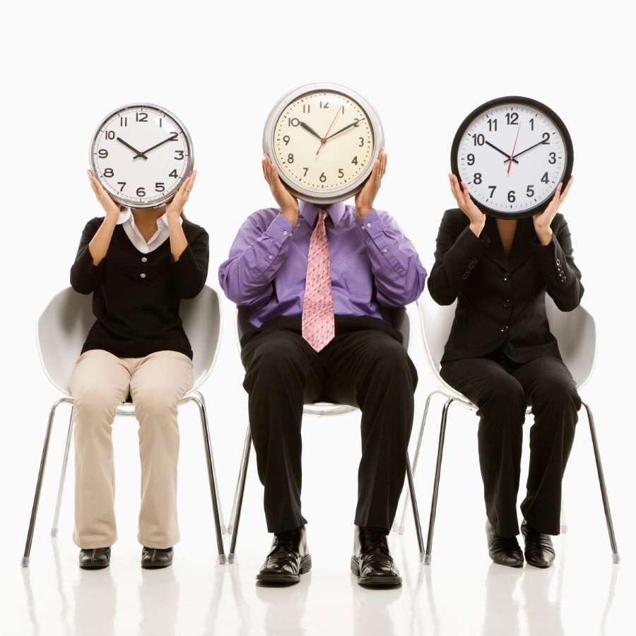 Time business concept. Multi-ethnic business people sitting holding clocks over faces.