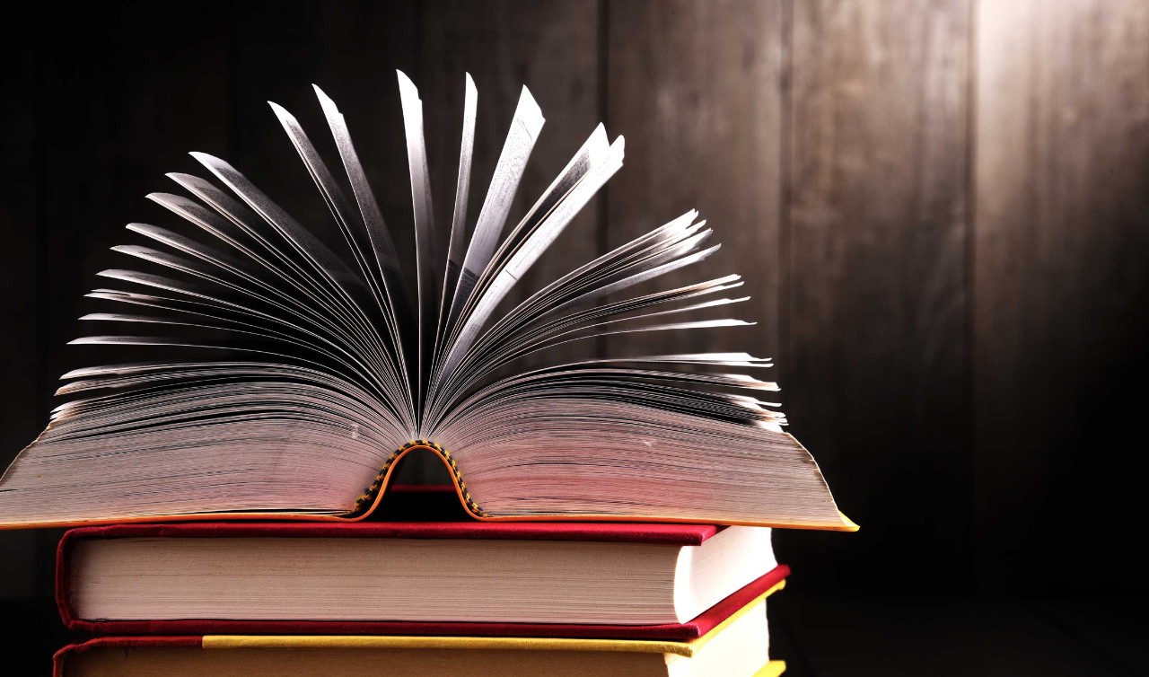 stack of books with a book flipped open on top
