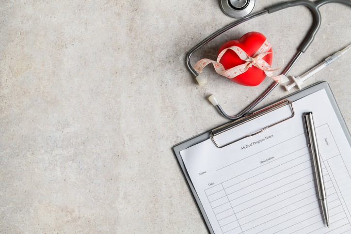 clipboard, stethoscope, and red heart on gray background