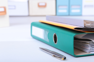 stack of binders and pen on white desk