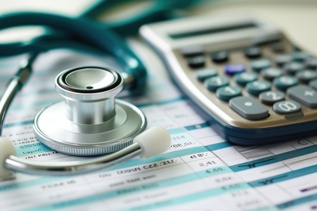 calculator and stethoscope on top of paperwork